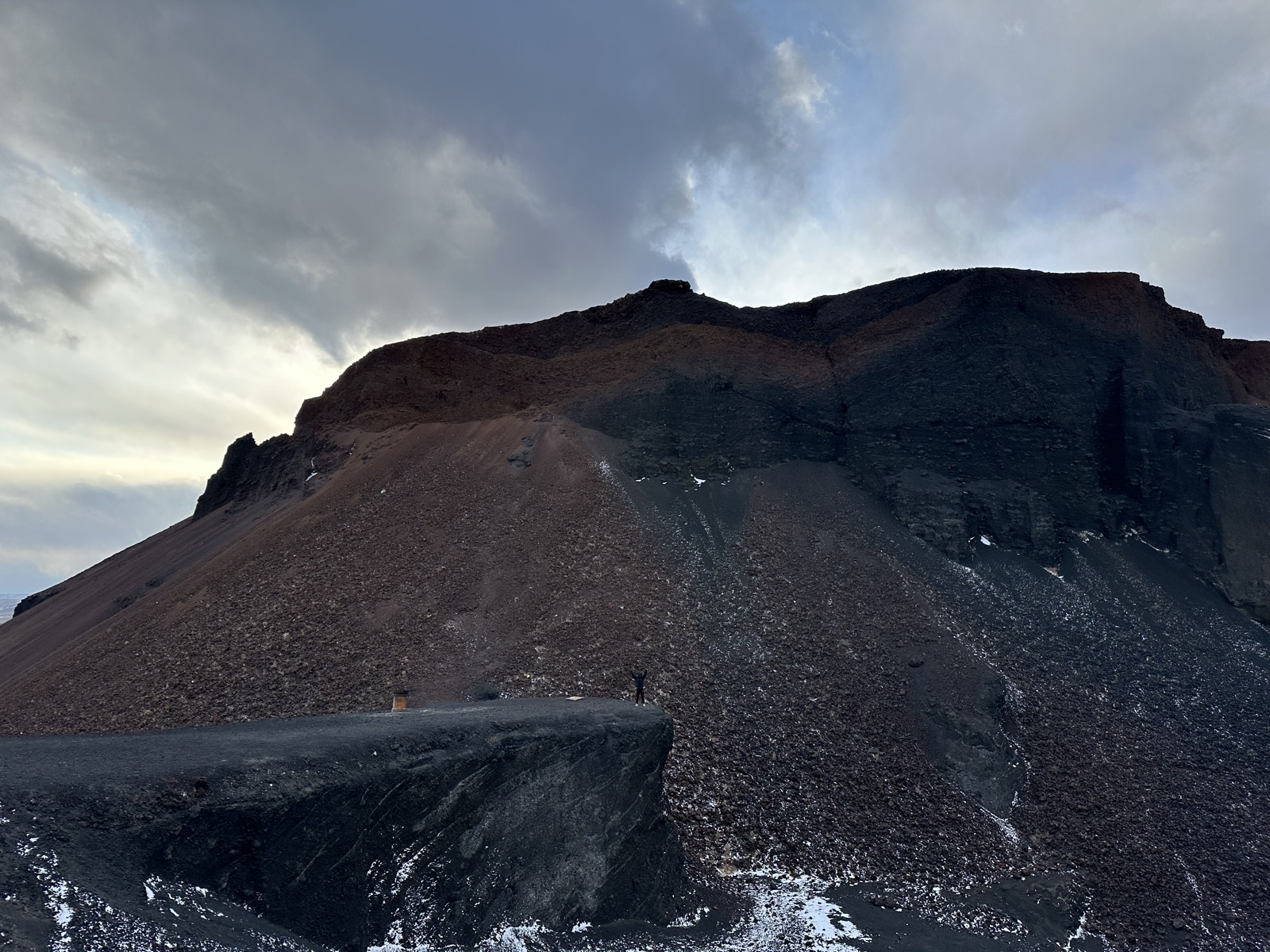 乌兰察布火山群深色岩壁与残雪形成清晰的地层纹理