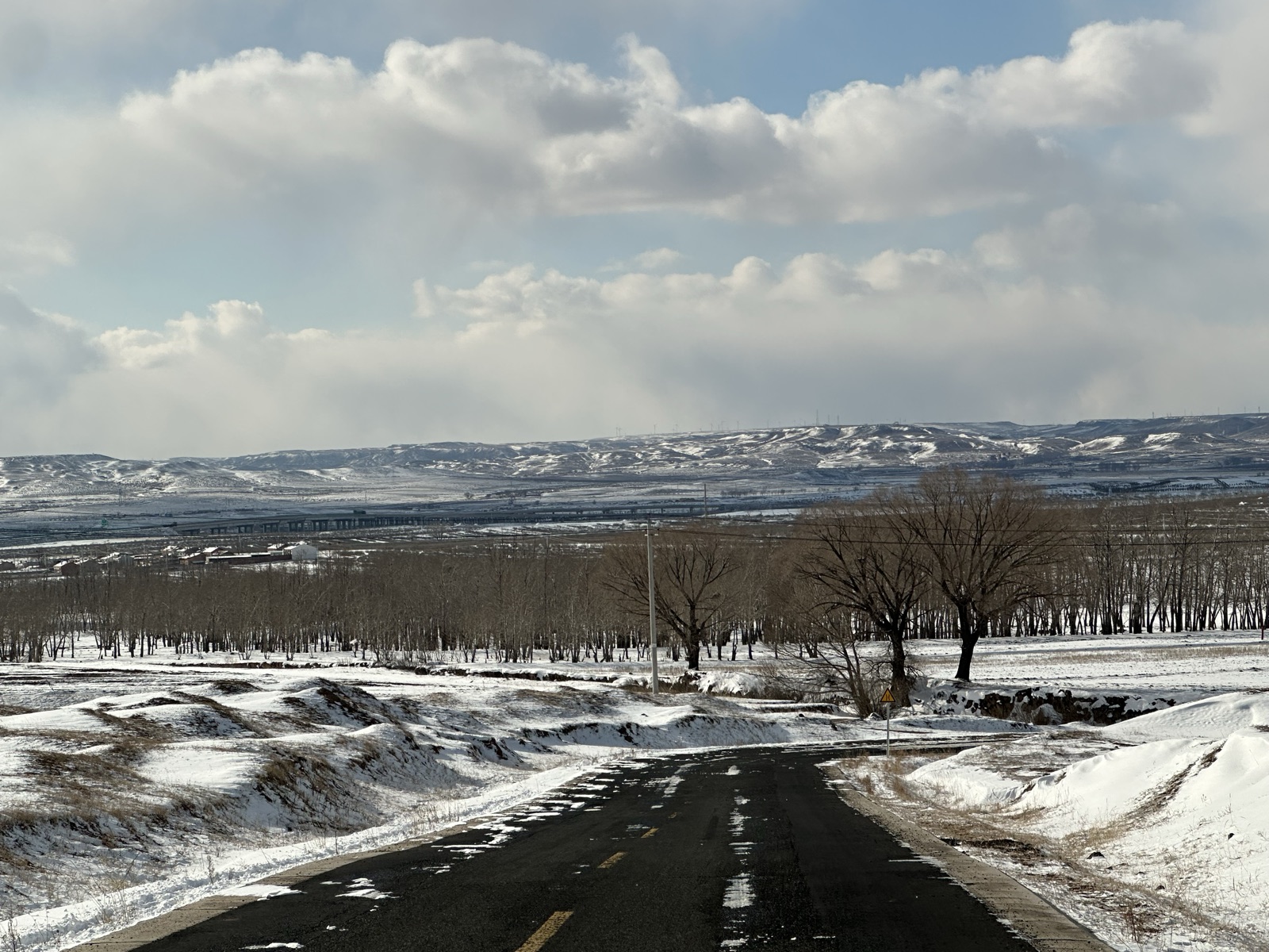积雪山谷、林地与远处公路在云下展开