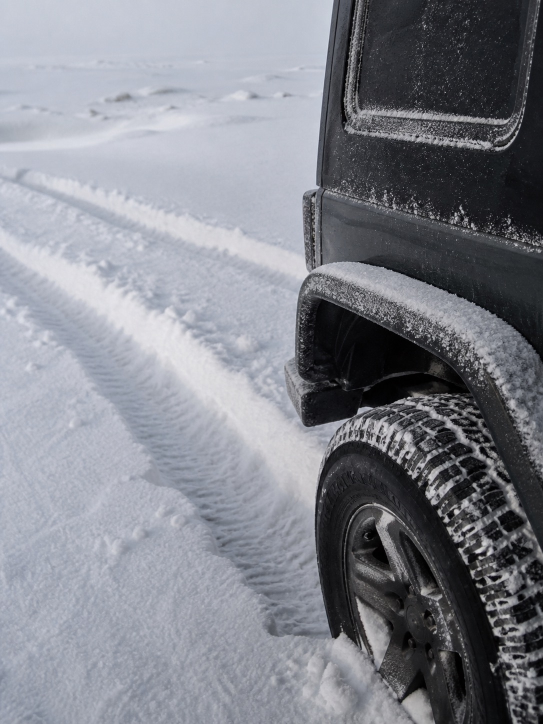 雪地车辙旁覆着冰霜的越野车后轮
